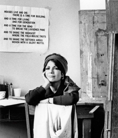A woman in a hat and gloves standing next to a table. A woman in a hat and gloves standing next to a table.