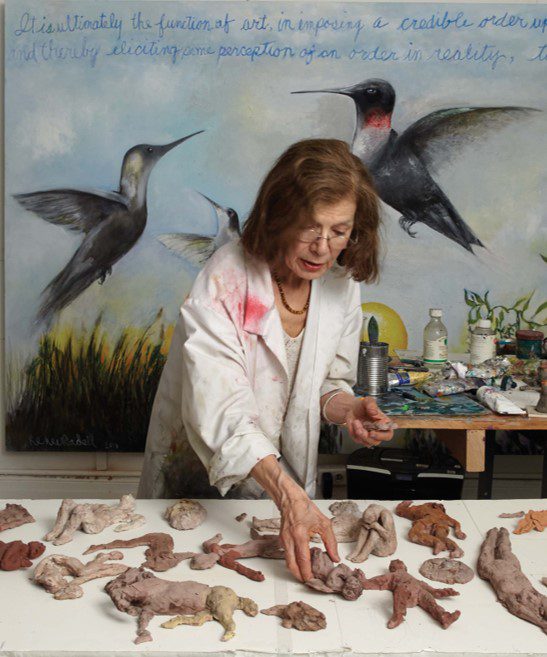 A woman in white shirt and black jacket near table with bird figurines. A woman in white shirt and black jacket near table with bird figurines.