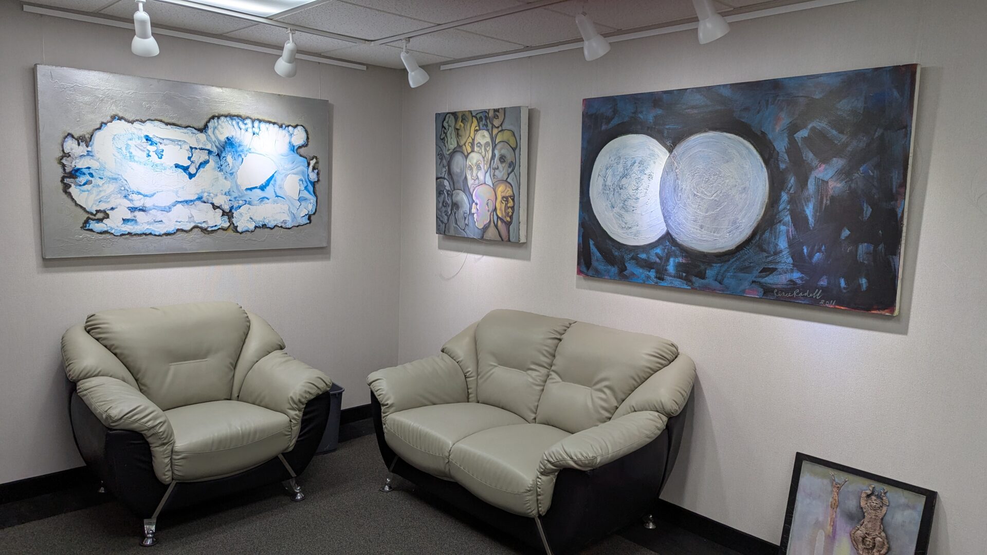 Modern art displayed above comfortable sofas in a cozy gallery corner.